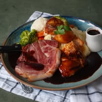 Roast gammon dinner with mashed potato, vegetables and gravy